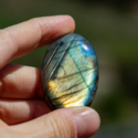 Pierre labradorite tenue entre 2 doigts